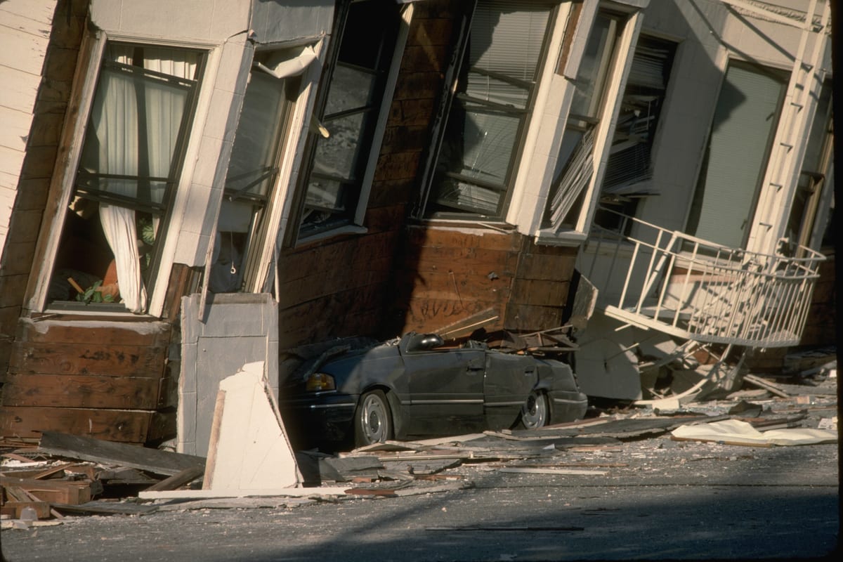 Row houses damaged in the 1989 Loma Prieta earthquake, one fallen onto a parked vehicle. Photo: U.S. Geological Survey.