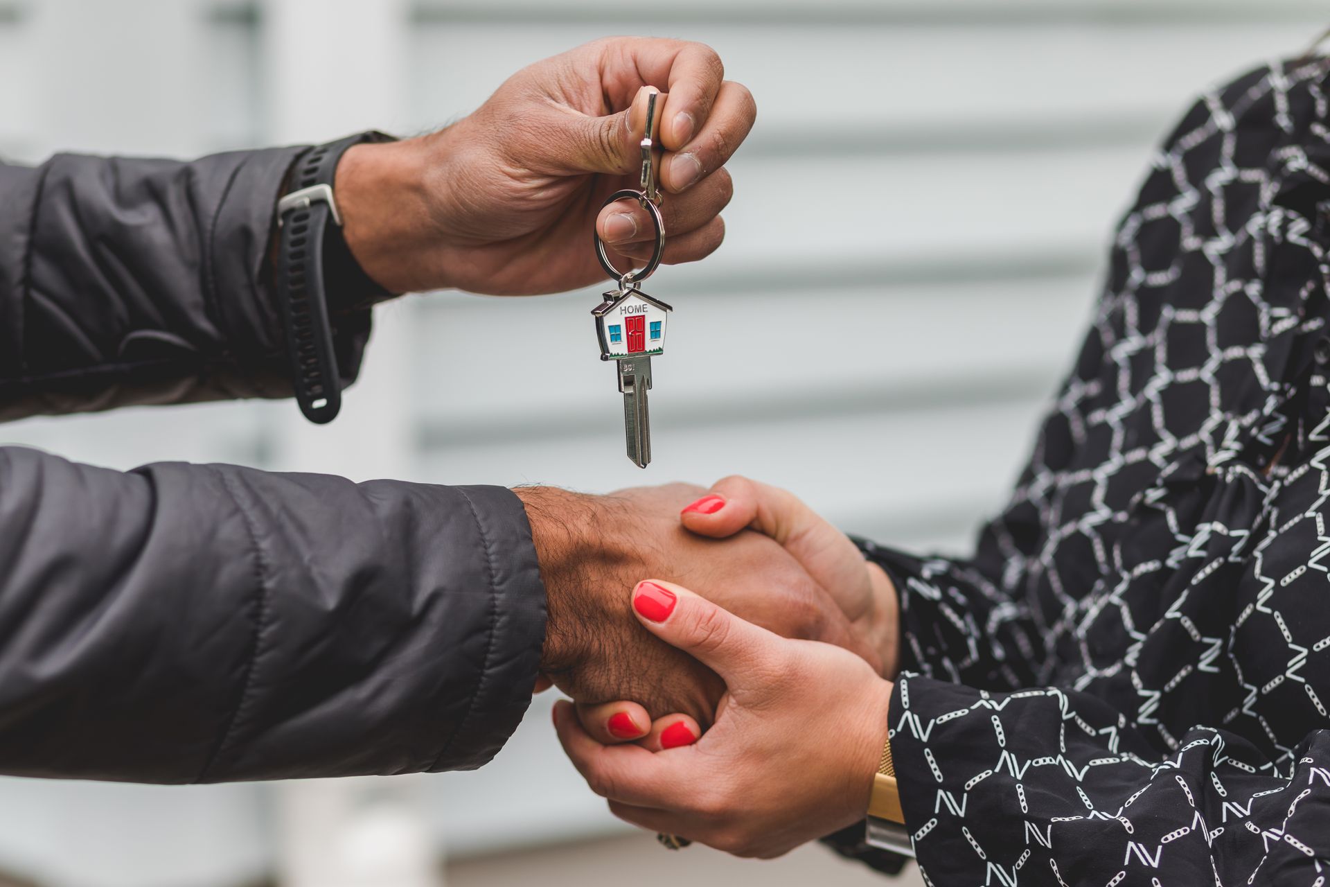 One person handing a house key to another with a handshake