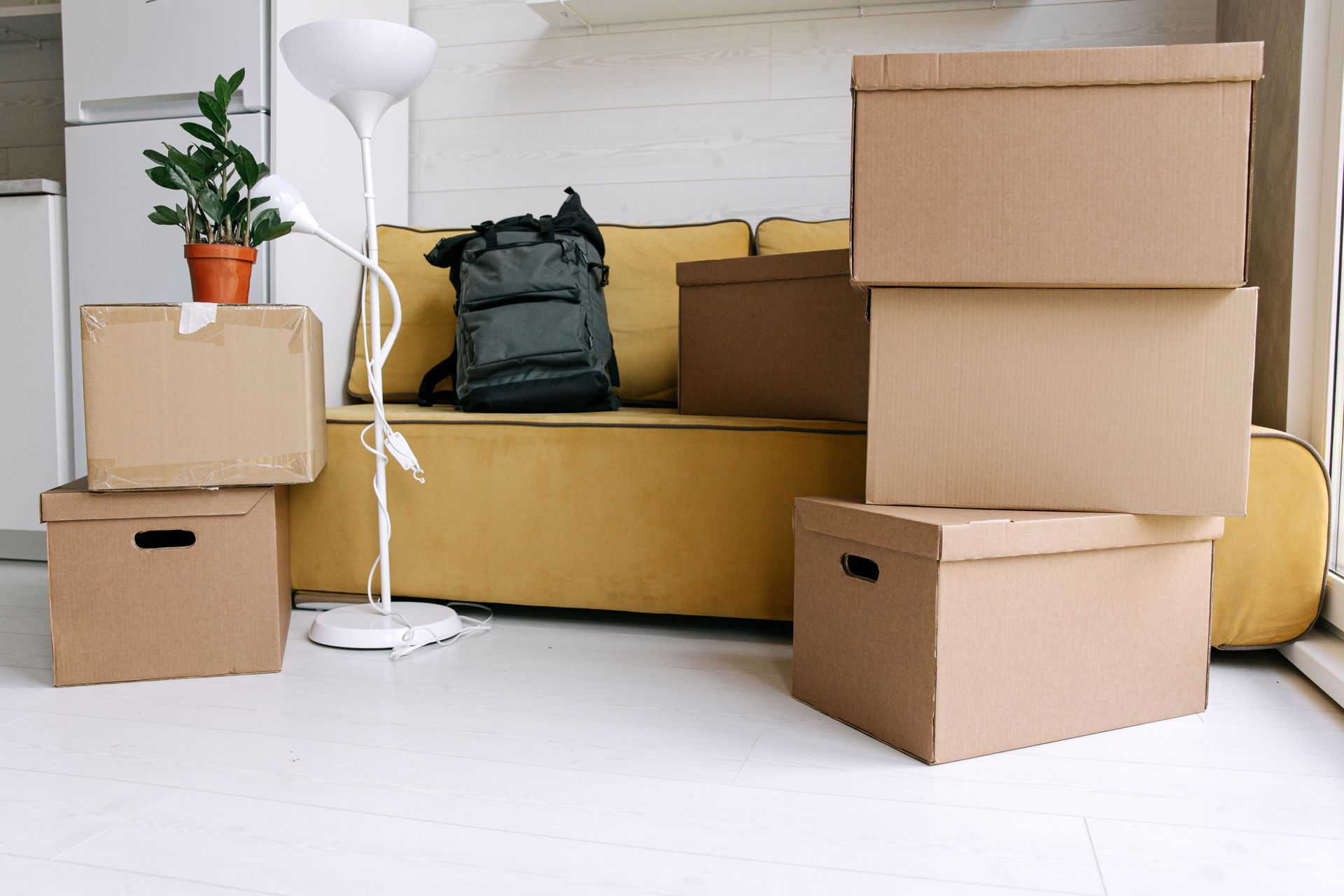 Moving boxes stacked around a yellow couch in an apartment